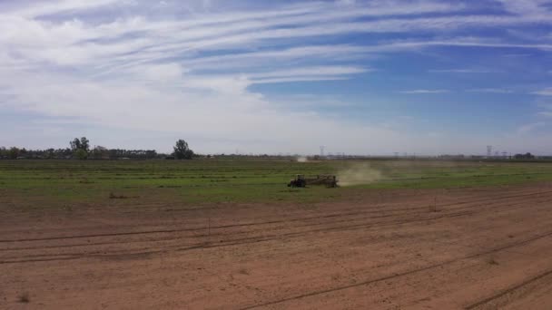 カリフォルニアのセントラルバレーの農地にフィールドを耕すトラクターの低幅の空中ショット — ストック動画