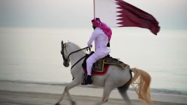 Caballero Montando Caballo Corriendo Sosteniendo Bandera Qatar Cerca Del Mar — Vídeos de Stock