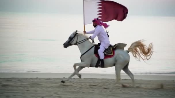 Caballero Montando Caballo Corriendo Sosteniendo Bandera Qatar Cerca Del Mar — Vídeos de Stock