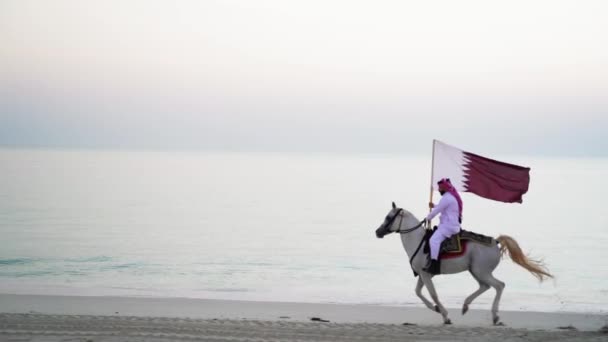 Rycerz Jeżdżący Koniu Trzymający Katarską Flagę Pobliżu Morza — Wideo stockowe