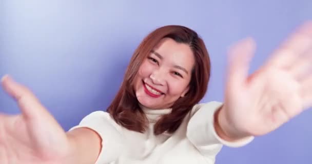 アジアの幸せな女性の肖像画は カメラに手を振っているとバイオレットの背景に隔離されたままハロージェスチャーを行う — ストック動画
