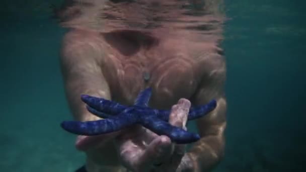 Hombre Sosteniendo Dos Estrellas Mar Azules Una Mano Bajo Agua — Vídeo de stock