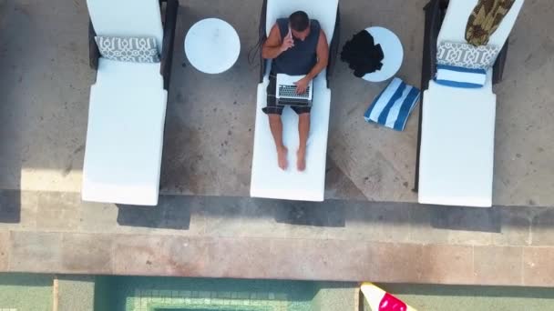 Беспилотный Снимок Человека Работающего Над Проектом Ноутбуке Сидящего Рядом Бассейном — стоковое видео