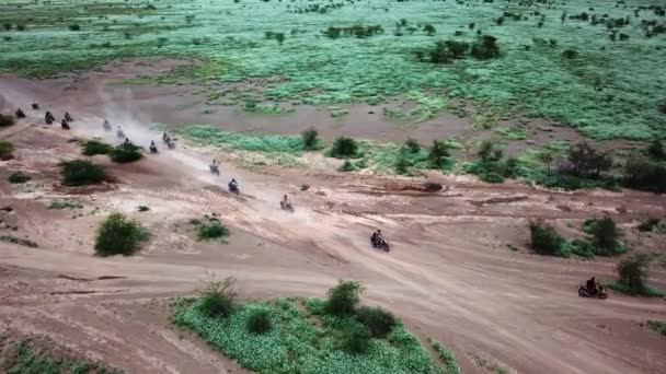 東アフリカのケニアの荒野をドライブするオートバイのライダーの巨大なグループ 空中射撃 — ストック動画