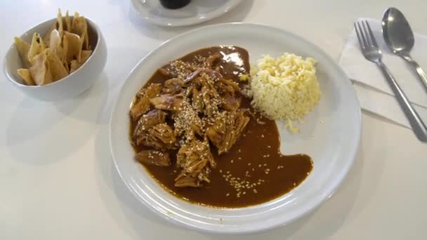 鶏とメキシコのモルソース テーブルの上に白いプレートにご飯と伝統的なモルポブラノ — ストック動画