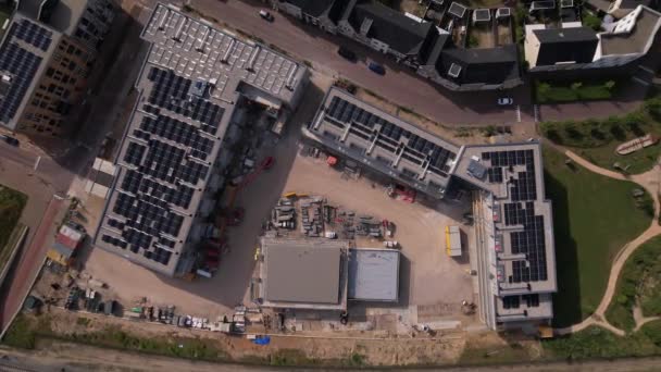 空中トップダウンアプローチ都市開発におけるUbuntuの建設現場屋根の上に太陽光パネルを備えた新しいNoorderhave地区の不動産投資プロジェクト — ストック動画
