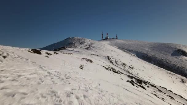 当徒步旅行者在雪山顶上走过时 向天线站飞去 — 图库视频影像