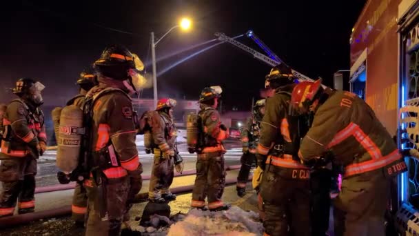 カナダのトロントの雪の降る夜の街で対応する準備をしている全体と酸素設備で完全な鎧を着た消防士のグループ — ストック動画