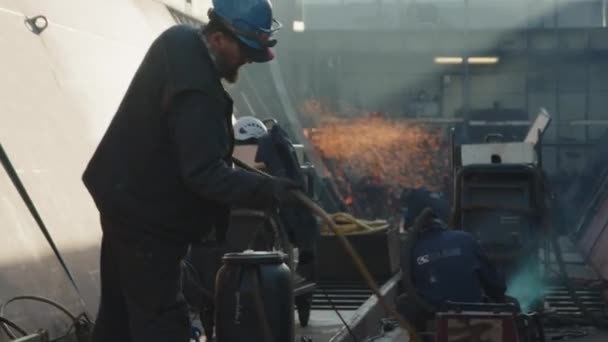 船厂里戴头盔的工人拿起并解开软管 — 图库视频影像