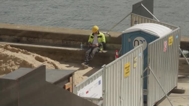 Pracownik Trudnych Warunkach Siedzący Nadmorskiej Promenadzie Przy Użyciu Smartfona Podczas — Wideo stockowe