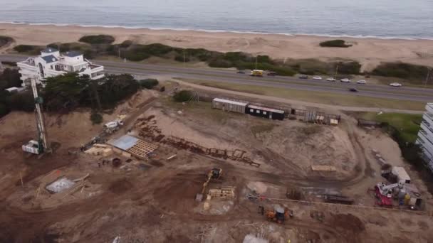 プンタ エステの海と砂浜の前の建設現場の空中ビュー 沿岸道路の車に沿って運転 — ストック動画