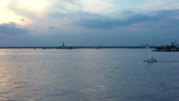 背景に自由の女神とニューヨーク港の夕暮れ時の帆船の空中映像 — ストック動画