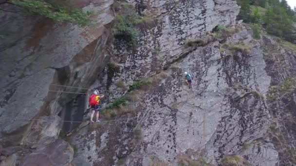 人々は地面の上に高い山のクロスロープの橋を登る アクロフォビアの場所はない ハイキング中の無人偵察機 — ストック動画