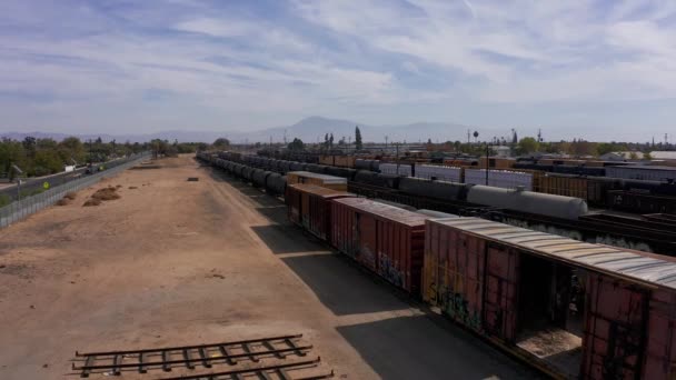 カリフォルニア州ベーカーズフィールド郊外の工業用鉄道ヤードでの貨物列車のロークローズアップ空撮 — ストック動画