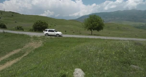 ジョージア州南部のAspindza外の芝生畑の間の田舎道に駐車された白い車 ドローン フライング — ストック動画