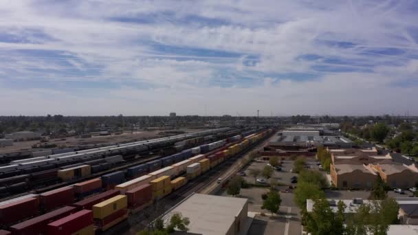 カリフォルニア州ベーカーズフィールド中心街の鉄道ヤードを通過する貨物列車の後の低空対空砲 — ストック動画