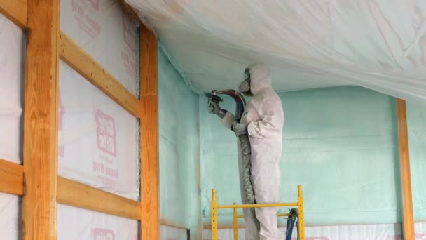 Man Disposable Tyvek Suit Respirator Spraying Foam Insulation Ceiling Exterior — Stock Video