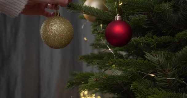 Frauenhände Legen Eine Goldene Kugel Auf Den Weihnachtsbaum Aus Nächster — Stockvideo