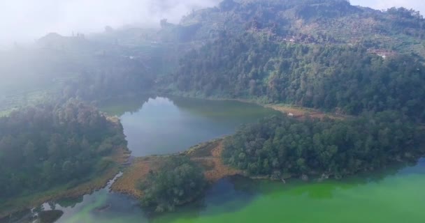 夏のジャワ島中部の山の上に熱帯湖と雲がある風光明媚な風景の上のシネマティックドローン飛行 — ストック動画
