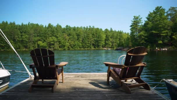 Dos Sillas Muskoka Vacías Sientan Final Muelle Mirando Agua Tranquilo — Vídeos de Stock