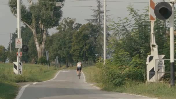 Bicyclist Pedaling Small Country Road Away Room Passing Railroad Crossing — Stock Video