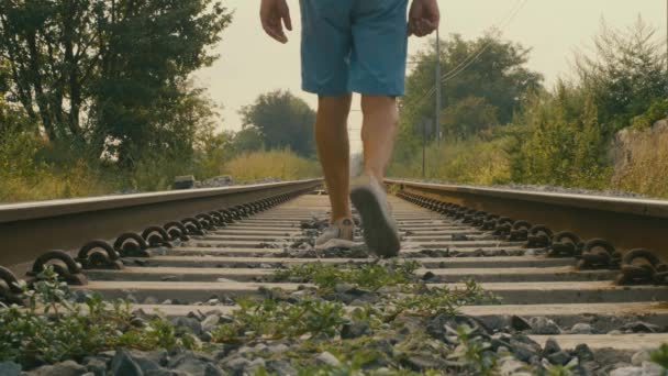 線路の中を歩く足の詳細 男は背を向けて暑い夏の日にトラックの中を進む — ストック動画