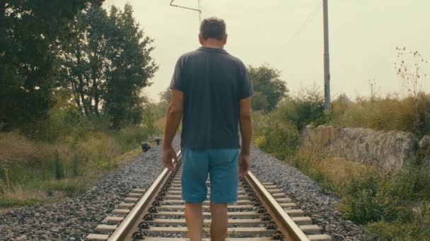 Ein Mann Geht Auf Den Gleisen Eines Verlassenen Bahnhofs Mitten — Stockvideo
