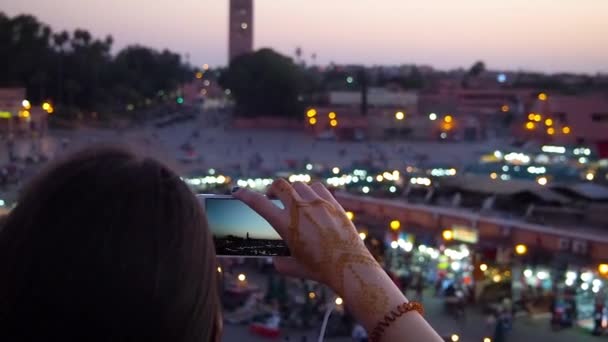 4K映像の女性が屋上でスマートフォンで写真を撮る Dejemaa Fnaa市場での耐久性のある日没 — ストック動画