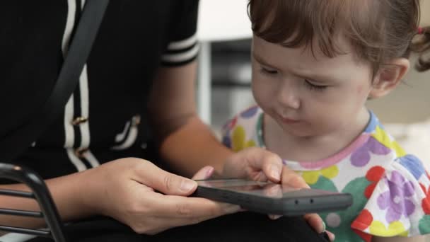 女人的手在用手机 而2岁的小女孩在用玩具智能手机打电话 带着手机的母亲和婴儿 慢动作 — 图库视频影像