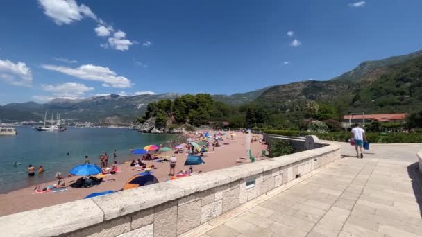 美しい日当たりの良いビーチと大きな石造りの橋は スヴェティ シュテファン Sveti Stefan と呼ばれるモンテネグロの有名な場所にあります — ストック動画