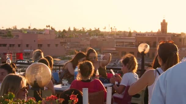 4K映像モロッコ マラケシュのデメマー フナア市場の日没時に屋上でスマートフォンで写真を撮る女性観光客 — ストック動画