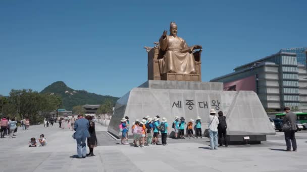 2022年にリニューアルオープンした光化門広場 ソウル 青空の晴れた日に聖宗大王像の前で旅行中に写真を撮る韓国の子供たちのグループ コピースペース — ストック動画