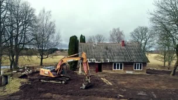 Drönare Fångade Grävmaskin Som Rev Upp Jorden Framför Liten Stuga — Stockvideo