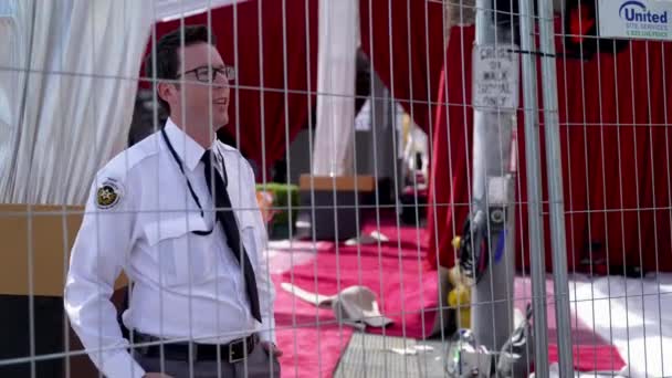 Ένας Φρουρός Ασφαλείας Στέκεται Πίσω Από Ένα Φράχτη Στο Κόκκινο — Αρχείο Βίντεο