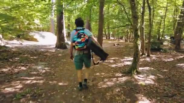 カラフルなバッグを持った男がフォンテーヌブローの森をクラッシュパッドで歩く — ストック動画