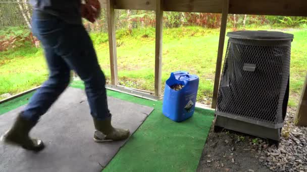 将空枪弹扔进塑料容器中循环利用金属的人 在室外射击场收集黄铜弹壳的蓝色垃圾桶 — 图库视频影像