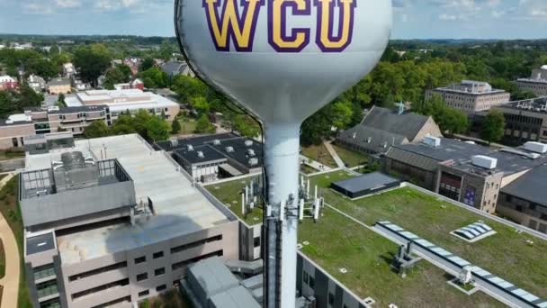 大学キャンパスの給水塔 ウェストチェスター大学のロゴと大型タンクの空中上昇ビュー — ストック動画