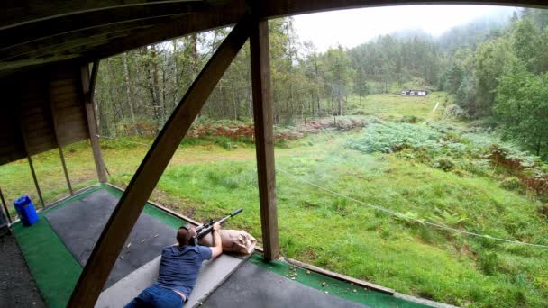 射撃場から遠く離れた標的を狙い 射撃する男 緑の森の田園地帯の射撃場でライフル射撃を敷設し 発射する一人 広い角度静的 — ストック動画