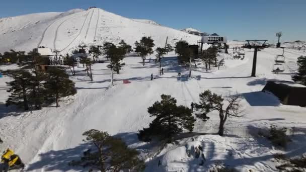 丘の上のスキー場の空中ビューは 背後に雪の山を明らかに — ストック動画