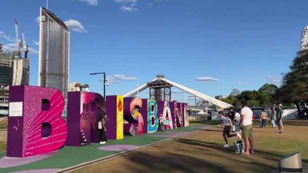 游客们参观了标志性的河岸地标 澳大利亚昆士兰州布里斯班市的一个五彩斑斓的大块标志 背景是正在建设的跨河大桥 — 图库视频影像