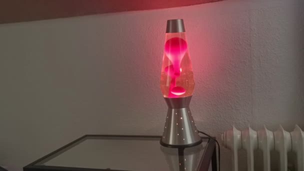 Gloeiende Borrelende Lavalamp Een Glazen Tafel Naast Een Wandradiator — Stockvideo