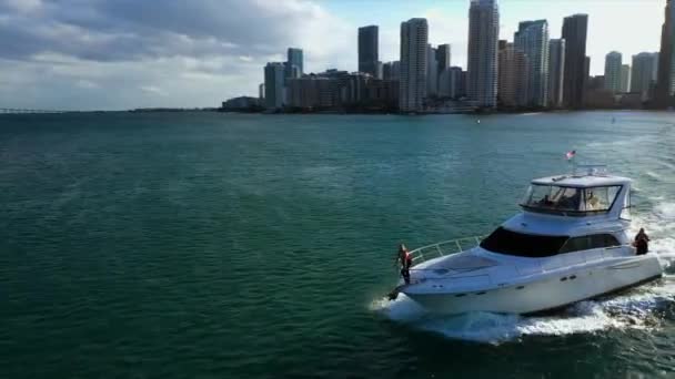 マイアミのスカイラインの前を走るヨットのデッキに立つ女性の周りの空中の景色 — ストック動画