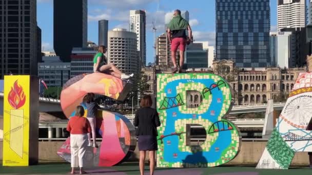 在澳大利亚昆士兰州的一个阳光明媚的日子里 游客们在色彩斑斓的大字上来回爬行 与布里斯班市的标志性地标合影 近距离近距离拍摄手持动作 — 图库视频影像