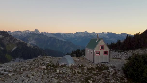 不列颠哥伦比亚落日落山上的孤零零的小木屋 四周环绕着落基景观 树上长满了树木 — 图库视频影像
