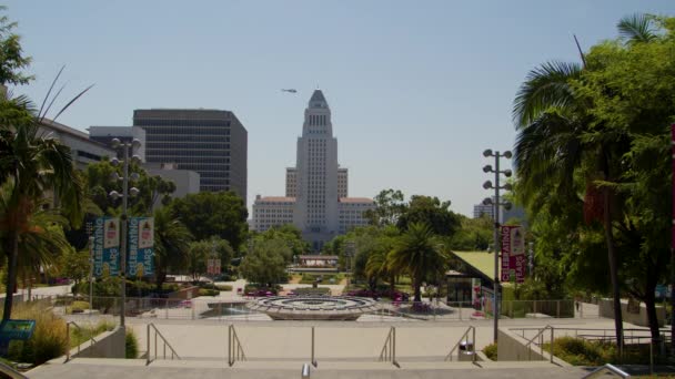 洛杉矶市政厅 Los Angeles City Hall 洛杉矶市长办公室和市议会的所在地 位于加利福尼亚州洛杉矶 夏季的一个大公园 一架直升机飞过去了 也可以看到喷泉和棕榈树 — 图库视频影像