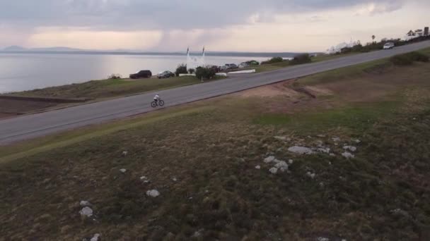 日没時に海を背景に斜面にマウンテンバイクに乗るスポーツサイクリスト プンタバレナ ウルグアイ — ストック動画
