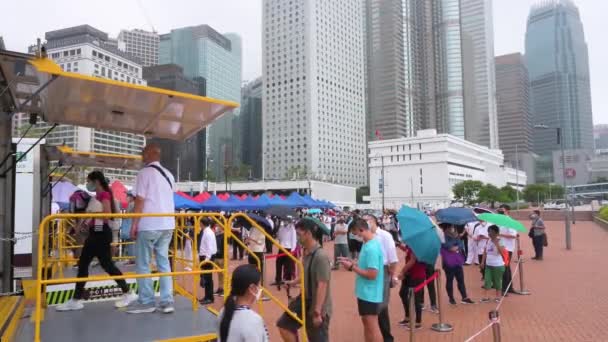 香港の金融街の近くでウイルスの拡散とパンデミックの波に対処するためにコミュニティテストセンターのトラックからコロナウイルス Covid のPcr検査を受けるために列に並ぶ人々 — ストック動画