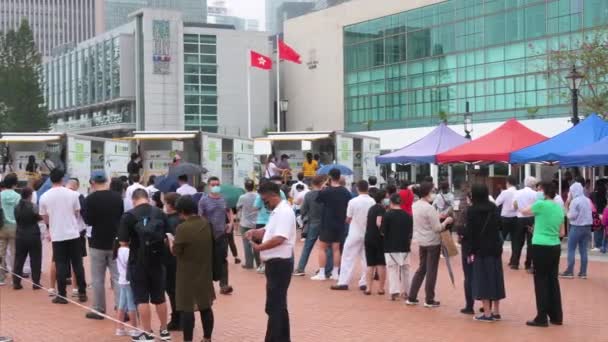 住民は 香港の金融街の近くにウイルスやパンデミックの波の普及に取り組むためにコミュニティテストセンタートラックからコロナウイルス Covid のPcr検査を受けるために列を作っています — ストック動画