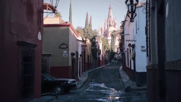 背景に教会 Parroquia San Miguel Arcngel があるSan Miguel Allendeの通りを歩いています — ストック動画