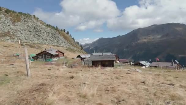 スイスの山の中の低フライオーバー小さな小屋風に舞うスイスの国旗 — ストック動画
